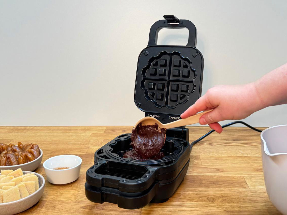 Das Bild zeigt, wie der Teig in das Waffelkucheneisen eingefüllt wird.