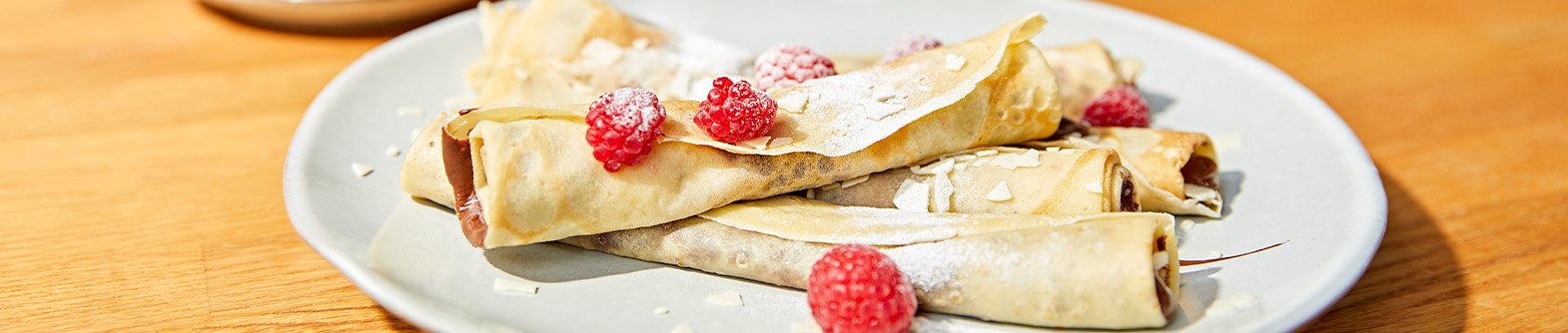 Das Bild zeigt Crêpes mit Himbeeren und Schokoladencreme.